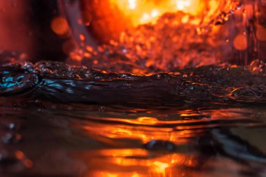 Bir volkanın lavında denizin taklidi, suyun dokusu kırmızı ışıkta çıkan hava kabarcıklarıyla kaos yaratıyor.