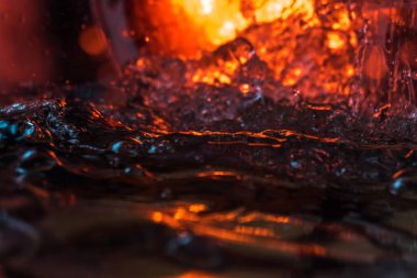 Bir volkanın lavında denizin taklidi, suyun dokusu kırmızı ışıkta çıkan hava kabarcıklarıyla kaos yaratıyor.