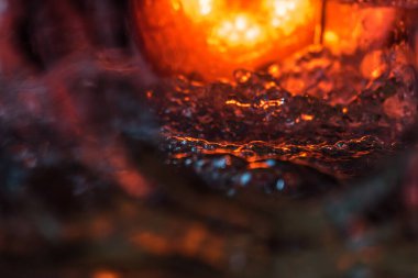 Bir volkanın lavında denizin taklidi, suyun dokusu kırmızı ışıkta çıkan hava kabarcıklarıyla kaos yaratıyor.