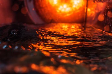 Bir volkanın lavında denizin taklidi, suyun dokusu kırmızı ışıkta çıkan hava kabarcıklarıyla kaos yaratıyor.