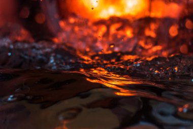 Bir volkanın lavında denizin taklidi, suyun dokusu kırmızı ışıkta çıkan hava kabarcıklarıyla kaos yaratıyor.