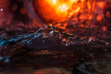 Bir volkanın lavında denizin taklidi, suyun dokusu kırmızı ışıkta çıkan hava kabarcıklarıyla kaos yaratıyor.