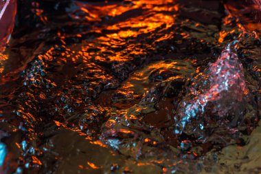 Bir volkanın lavında denizin taklidi, suyun dokusu kırmızı ışıkta çıkan hava kabarcıklarıyla kaos yaratıyor.