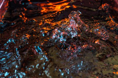 Bir volkanın lavında denizin taklidi, suyun dokusu kırmızı ışıkta çıkan hava kabarcıklarıyla kaos yaratıyor.