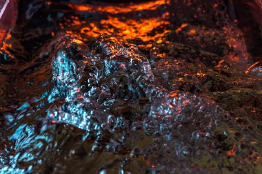 Bir volkanın lavında denizin taklidi, suyun dokusu kırmızı ışıkta çıkan hava kabarcıklarıyla kaos yaratıyor.