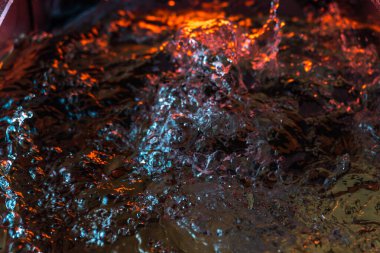 Bir volkanın lavında denizin taklidi, suyun dokusu kırmızı ışıkta çıkan hava kabarcıklarıyla kaos yaratıyor.