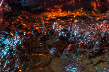 Bir volkanın lavında denizin taklidi, suyun dokusu kırmızı ışıkta çıkan hava kabarcıklarıyla kaos yaratıyor.