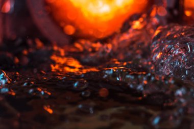 Bir volkanın lavında denizin taklidi, suyun dokusu kırmızı ışıkta çıkan hava kabarcıklarıyla kaos yaratıyor.