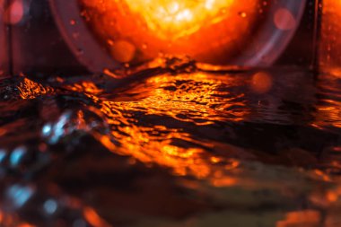 Bir volkanın lavında denizin taklidi, suyun dokusu kırmızı ışıkta çıkan hava kabarcıklarıyla kaos yaratıyor.