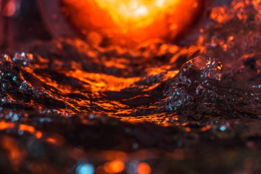 Bir volkanın lavında denizin taklidi, suyun dokusu kırmızı ışıkta çıkan hava kabarcıklarıyla kaos yaratıyor.