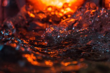 Bir volkanın lavında denizin taklidi, suyun dokusu kırmızı ışıkta çıkan hava kabarcıklarıyla kaos yaratıyor.