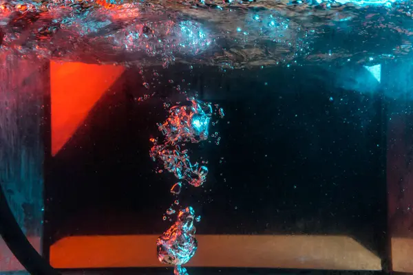 Su dokusu gürleyen kaos içinde hava kabarcıkları yaratıyor mavi ve kırmızı ışıkta dışarı kaçıyorlar.