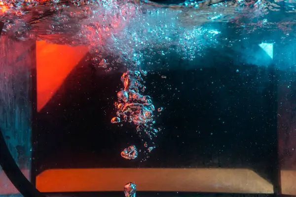 Su dokusu gürleyen kaos içinde hava kabarcıkları yaratıyor mavi ve kırmızı ışıkta dışarı kaçıyorlar.