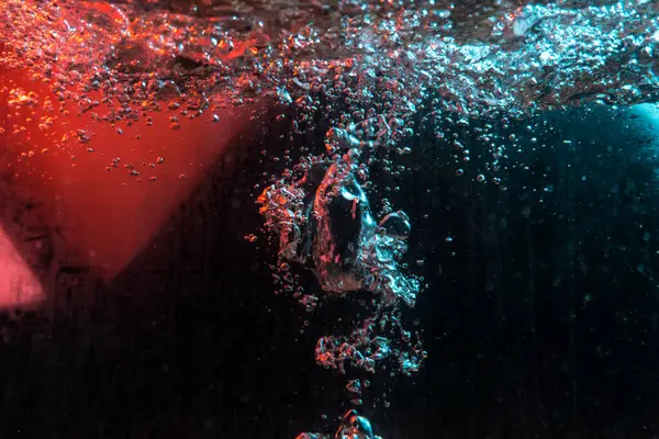 Su dokusu gürleyen kaos içinde hava kabarcıkları yaratıyor mavi ve kırmızı ışıkta dışarı kaçıyorlar.