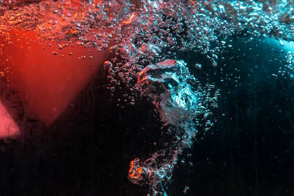 Su dokusu gürleyen kaos içinde hava kabarcıkları yaratıyor mavi ve kırmızı ışıkta dışarı kaçıyorlar.