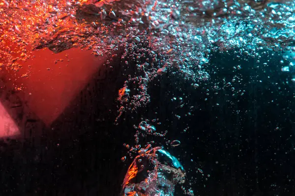 Su dokusu gürleyen kaos içinde hava kabarcıkları yaratıyor mavi ve kırmızı ışıkta dışarı kaçıyorlar.