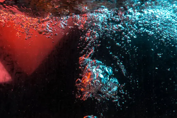 Su dokusu gürleyen kaos içinde hava kabarcıkları yaratıyor mavi ve kırmızı ışıkta dışarı kaçıyorlar.