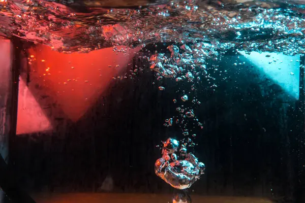 Su dokusu gürleyen kaos içinde hava kabarcıkları yaratıyor mavi ve kırmızı ışıkta dışarı kaçıyorlar.