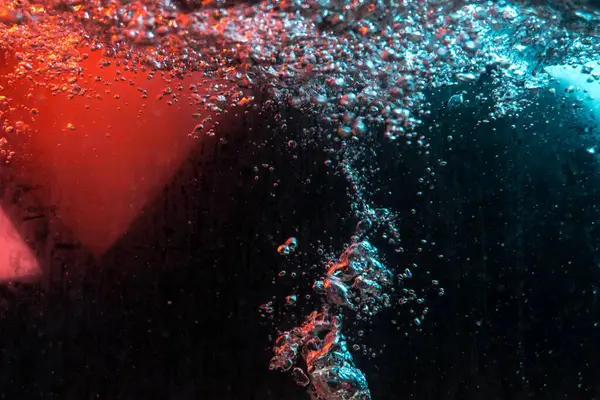 Su dokusu gürleyen kaos içinde hava kabarcıkları yaratıyor mavi ve kırmızı ışıkta dışarı kaçıyorlar.