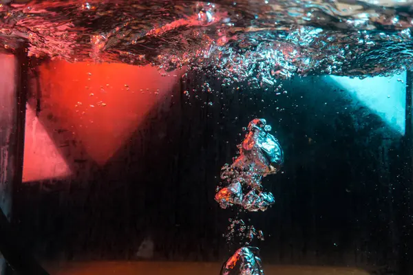 Su dokusu gürleyen kaos içinde hava kabarcıkları yaratıyor mavi ve kırmızı ışıkta dışarı kaçıyorlar.