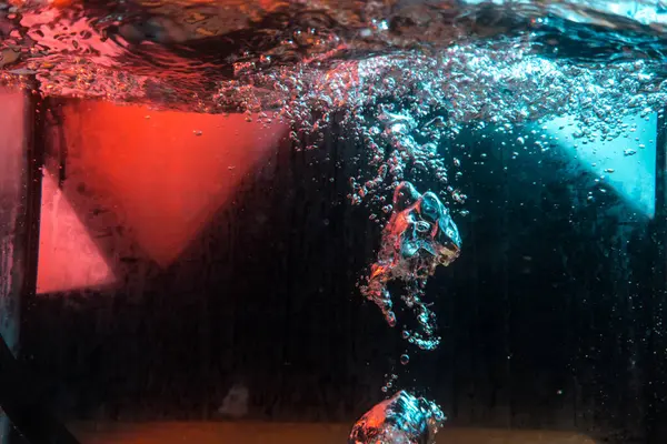 Su dokusu gürleyen kaos içinde hava kabarcıkları yaratıyor mavi ve kırmızı ışıkta dışarı kaçıyorlar.