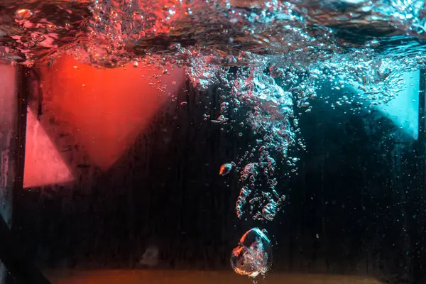 Su dokusu gürleyen kaos içinde hava kabarcıkları yaratıyor mavi ve kırmızı ışıkta dışarı kaçıyorlar.