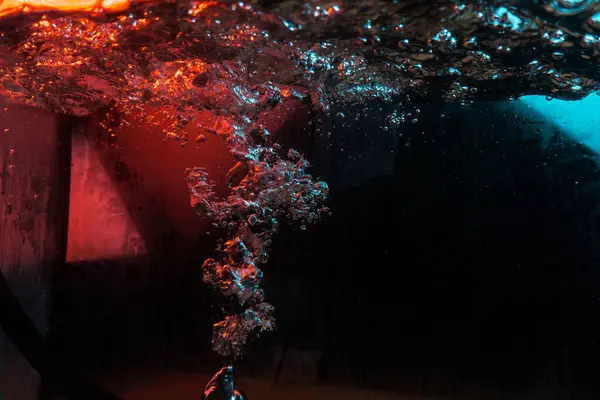 Su dokusu gürleyen kaos içinde hava kabarcıkları yaratıyor mavi ve kırmızı ışıkta dışarı kaçıyorlar.