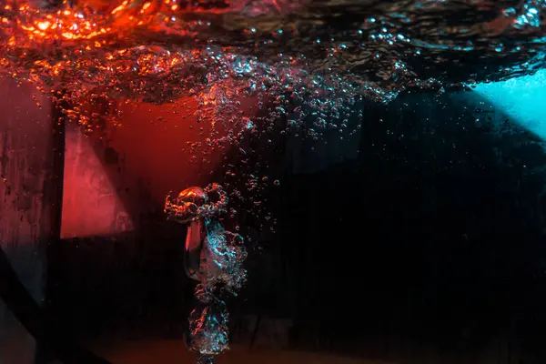 Su dokusu gürleyen kaos içinde hava kabarcıkları yaratıyor mavi ve kırmızı ışıkta dışarı kaçıyorlar.