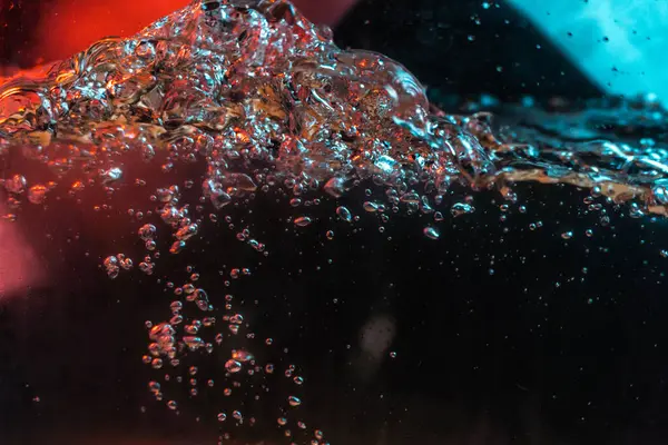 Su dokusu gürleyen kaos içinde hava kabarcıkları yaratıyor mavi ve kırmızı ışıkta dışarı kaçıyorlar.