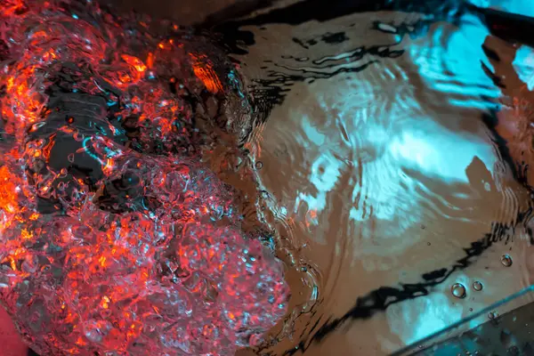 Su dokusu gürleyen kaos içinde hava kabarcıkları yaratıyor mavi ve kırmızı ışıkta dışarı kaçıyorlar.