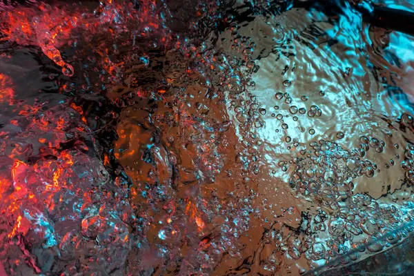 Su dokusu gürleyen kaos içinde hava kabarcıkları yaratıyor mavi ve kırmızı ışıkta dışarı kaçıyorlar.