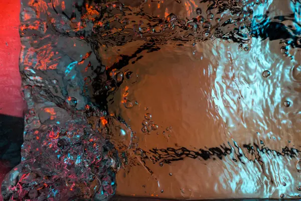 Su dokusu gürleyen kaos içinde hava kabarcıkları yaratıyor mavi ve kırmızı ışıkta dışarı kaçıyorlar.