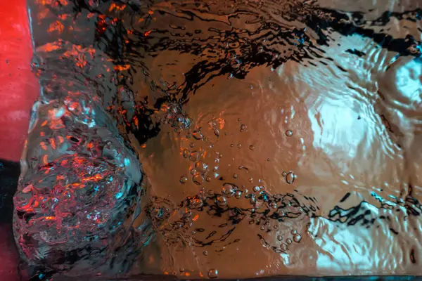 Su dokusu gürleyen kaos içinde hava kabarcıkları yaratıyor mavi ve kırmızı ışıkta dışarı kaçıyorlar.