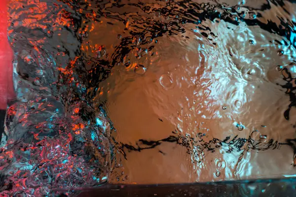 Su dokusu gürleyen kaos içinde hava kabarcıkları yaratıyor mavi ve kırmızı ışıkta dışarı kaçıyorlar.