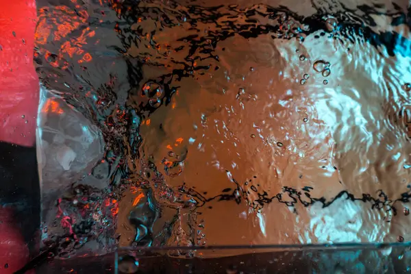 Su dokusu gürleyen kaos içinde hava kabarcıkları yaratıyor mavi ve kırmızı ışıkta dışarı kaçıyorlar.