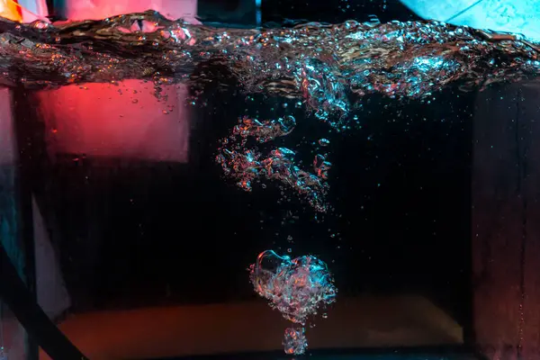 Su dokusu gürleyen kaos içinde hava kabarcıkları yaratıyor mavi ve kırmızı ışıkta dışarı kaçıyorlar.