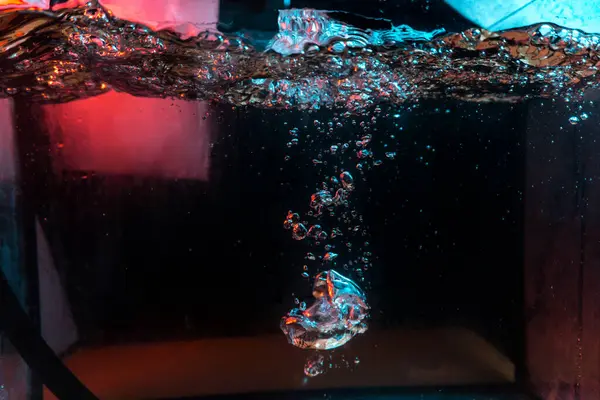 Su dokusu gürleyen kaos içinde hava kabarcıkları yaratıyor mavi ve kırmızı ışıkta dışarı kaçıyorlar.