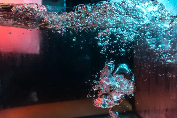 Su dokusu gürleyen kaos içinde hava kabarcıkları yaratıyor mavi ve kırmızı ışıkta dışarı kaçıyorlar.