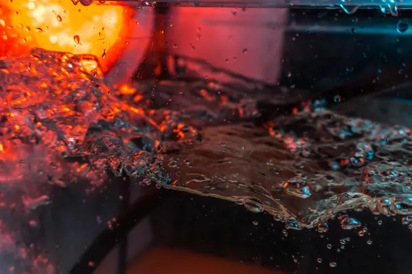 Bir volkanın lavında denizin taklidi, suyun dokusu kırmızı ışıkta çıkan hava kabarcıklarıyla kaos yaratıyor.