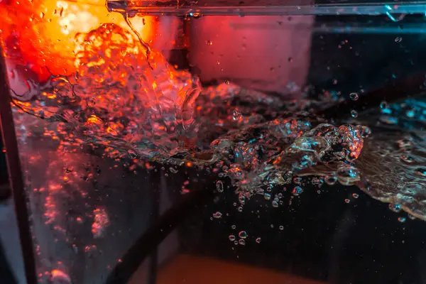 Bir volkanın lavında denizin taklidi, suyun dokusu kırmızı ışıkta çıkan hava kabarcıklarıyla kaos yaratıyor.