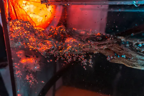 Bir volkanın lavında denizin taklidi, suyun dokusu kırmızı ışıkta çıkan hava kabarcıklarıyla kaos yaratıyor.