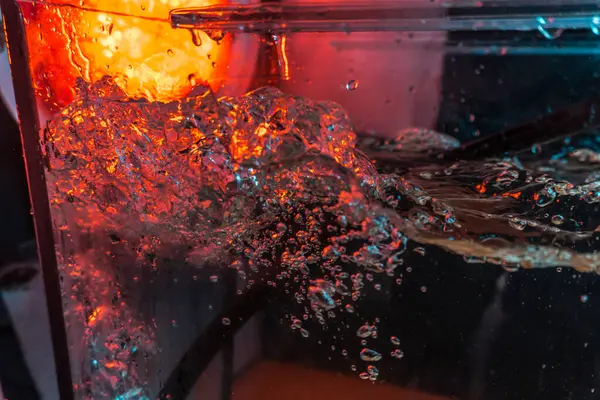 Bir volkanın lavında denizin taklidi, suyun dokusu kırmızı ışıkta çıkan hava kabarcıklarıyla kaos yaratıyor.