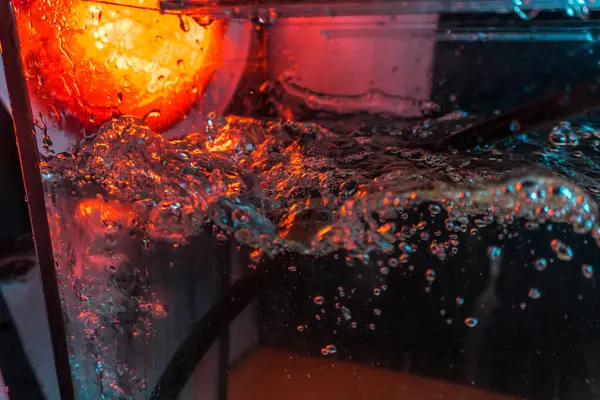 Bir volkanın lavında denizin taklidi, suyun dokusu kırmızı ışıkta çıkan hava kabarcıklarıyla kaos yaratıyor.