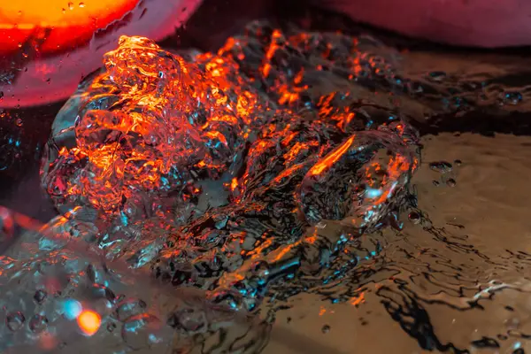 Bir volkanın lavında denizin taklidi, suyun dokusu kırmızı ışıkta çıkan hava kabarcıklarıyla kaos yaratıyor.