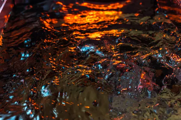 Bir volkanın lavında denizin taklidi, suyun dokusu kırmızı ışıkta çıkan hava kabarcıklarıyla kaos yaratıyor.