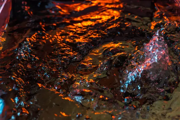 Bir volkanın lavında denizin taklidi, suyun dokusu kırmızı ışıkta çıkan hava kabarcıklarıyla kaos yaratıyor.