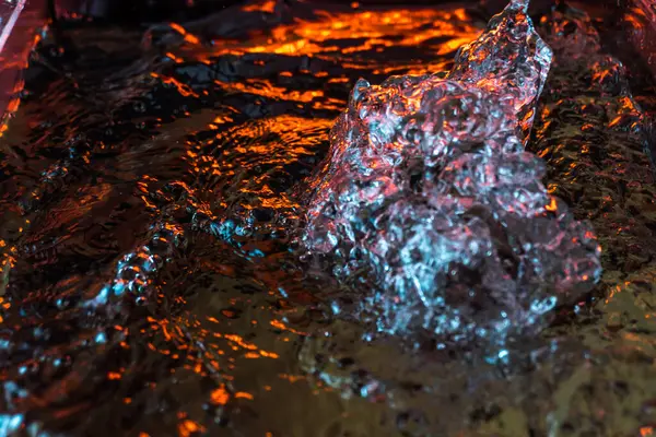 Bir volkanın lavında denizin taklidi, suyun dokusu kırmızı ışıkta çıkan hava kabarcıklarıyla kaos yaratıyor.