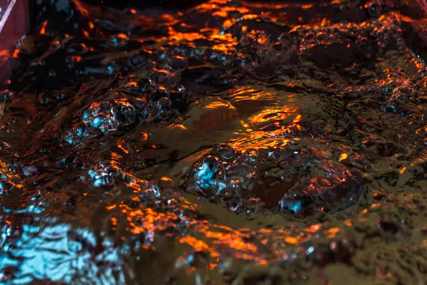 Bir volkanın lavında denizin taklidi, suyun dokusu kırmızı ışıkta çıkan hava kabarcıklarıyla kaos yaratıyor.