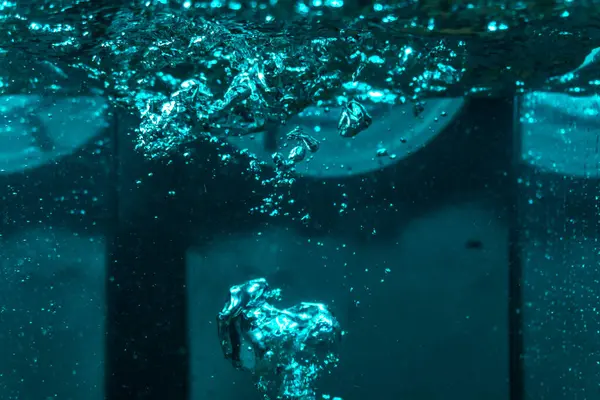 Suyun dokusu, hava kabarcıklarının oluşturduğu gürleyen bir kaostur. Mavi ışıkta dışarıya doğru kaçıyorlar.