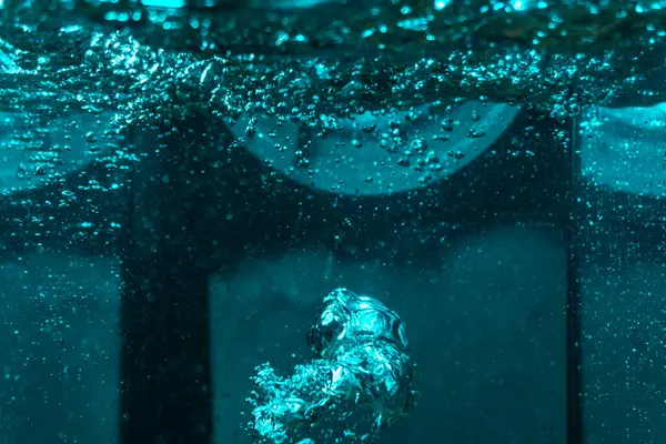 Suyun dokusu, hava kabarcıklarının oluşturduğu gürleyen bir kaostur. Mavi ışıkta dışarıya doğru kaçıyorlar.